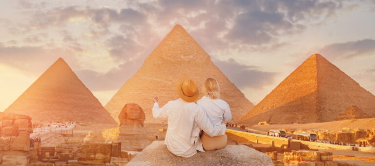Back view lover couple, Tourists woman and man with hat background Sphinx and pyramid of Egyptian Giza, sunset Cairo, Egypt.