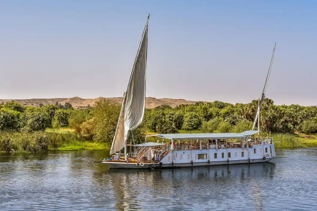 Sailing vessel on the river Nile close to the green shore and the desert