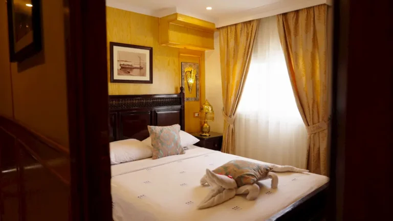 Amoura Dahabiya double cabin with decorative bedding and Nile-facing window