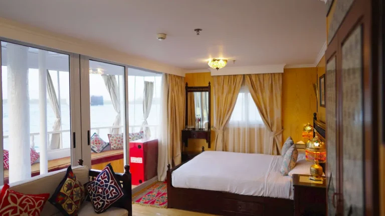 Spacious Amoura Dahabiya suite with a double bed and panoramic Nile windows