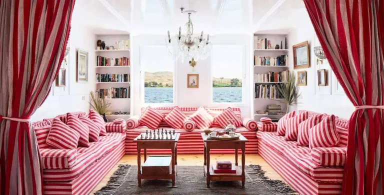 Elegant Dahabiya lounge with red-striped sofas, bookshelves and Nile views