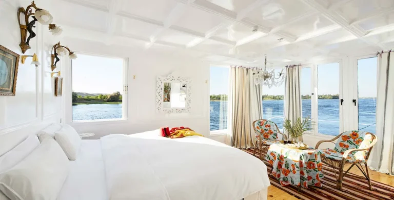 Luxury Dahabiya suite with floral seating and floor-to-ceiling Nile views